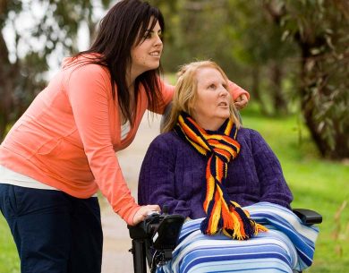 Two women out for a walk, enjoying the sunshine. One woman is in a wheelchair.